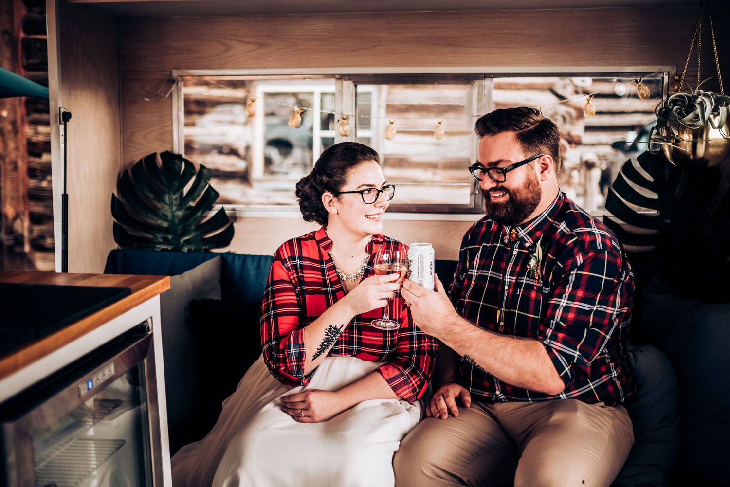 Couple sharing drinks at rustic venue with decorative plants.