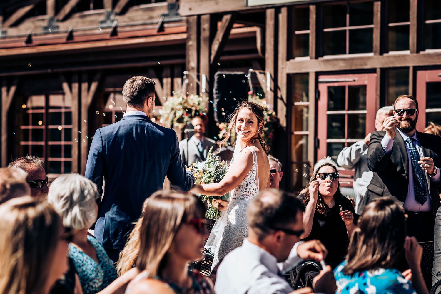 Wedding celebration at rustic wooden lodge with guests enjoying outdoor ceremony.