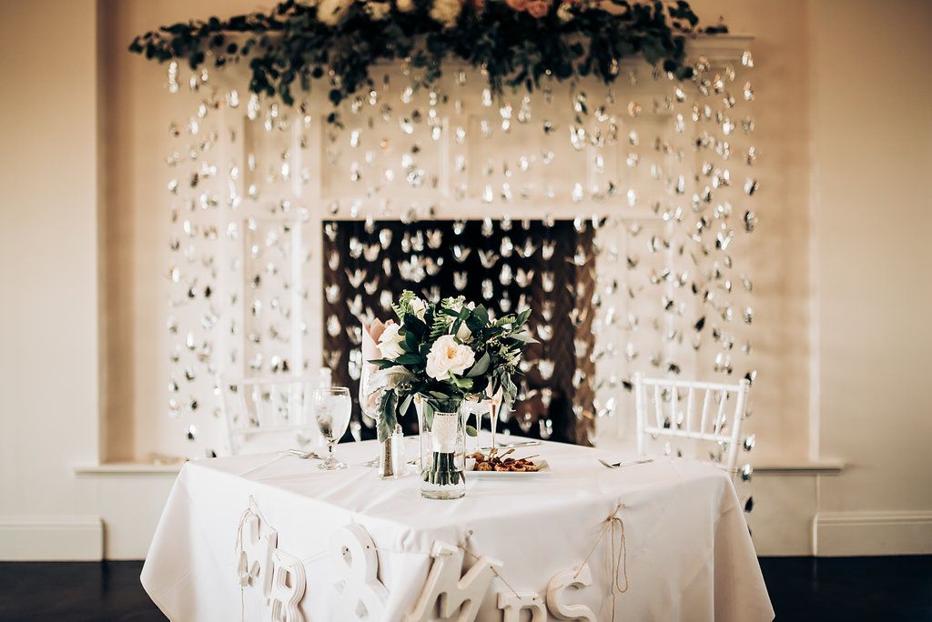 Elegant wedding head table setup with cascading floral arrangements and white crystal decorations.
