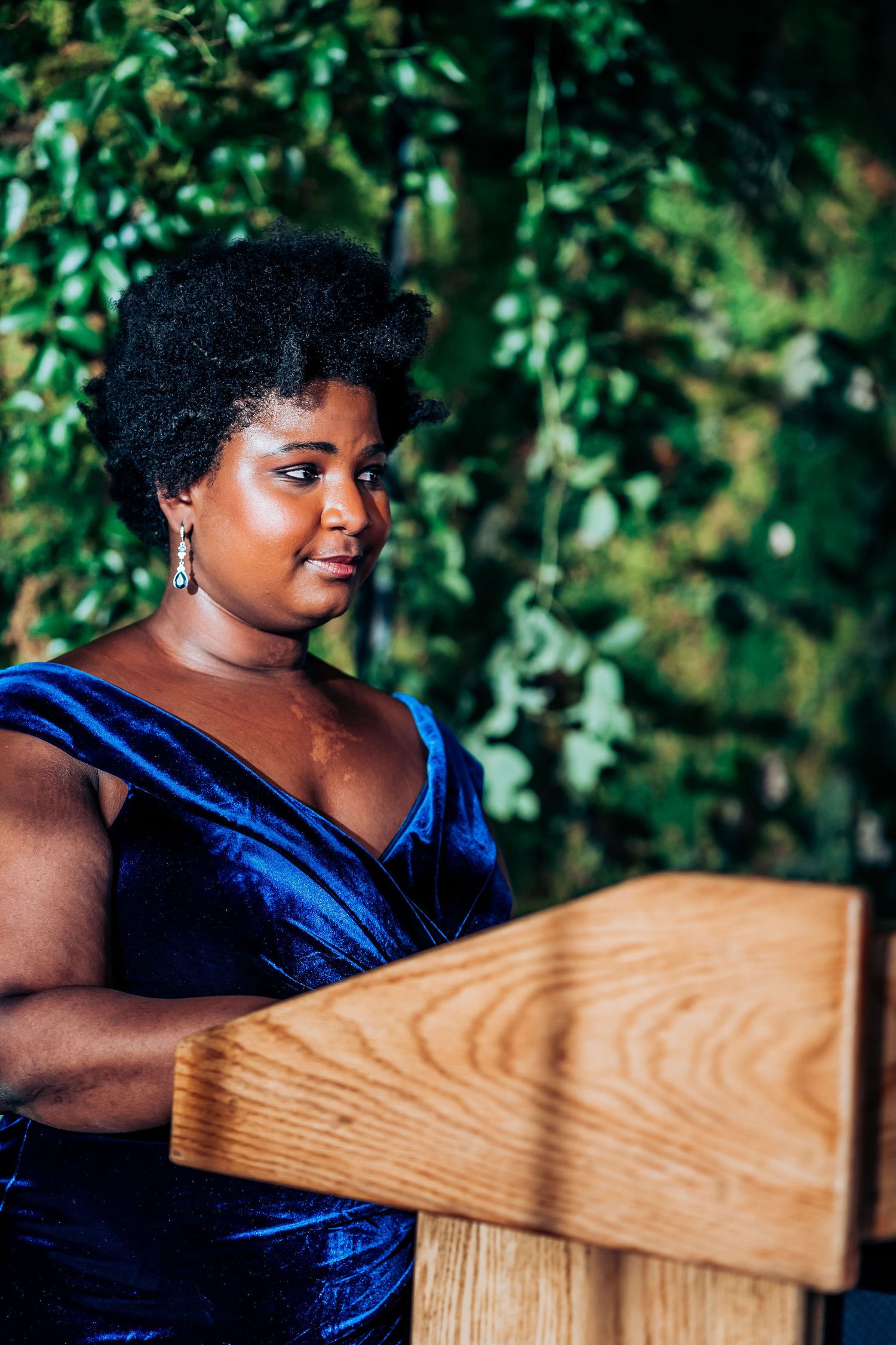 Speaker at podium wearing royal blue velvet dress during wedding ceremony.