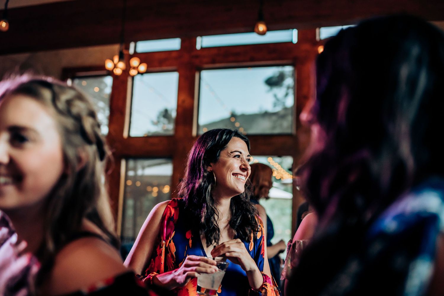 Guests share laughs and stories during a festive evening celebration with warm lighting.