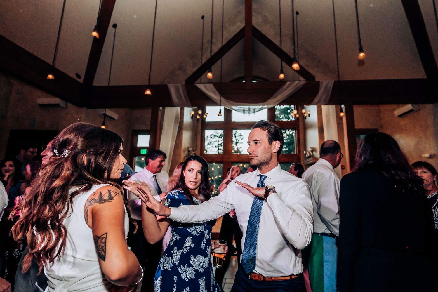 Wedding reception dance party in full swing with guests celebrating under vaulted ceilings.