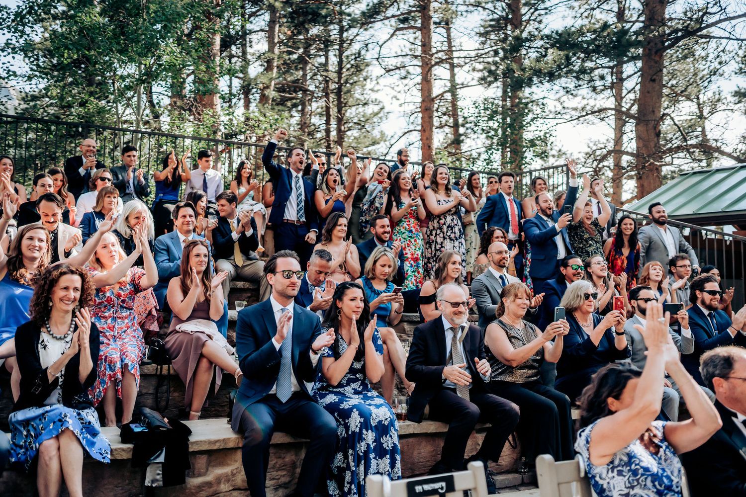 Wedding guests celebrate and cheer during outdoor mountain venue celebration.