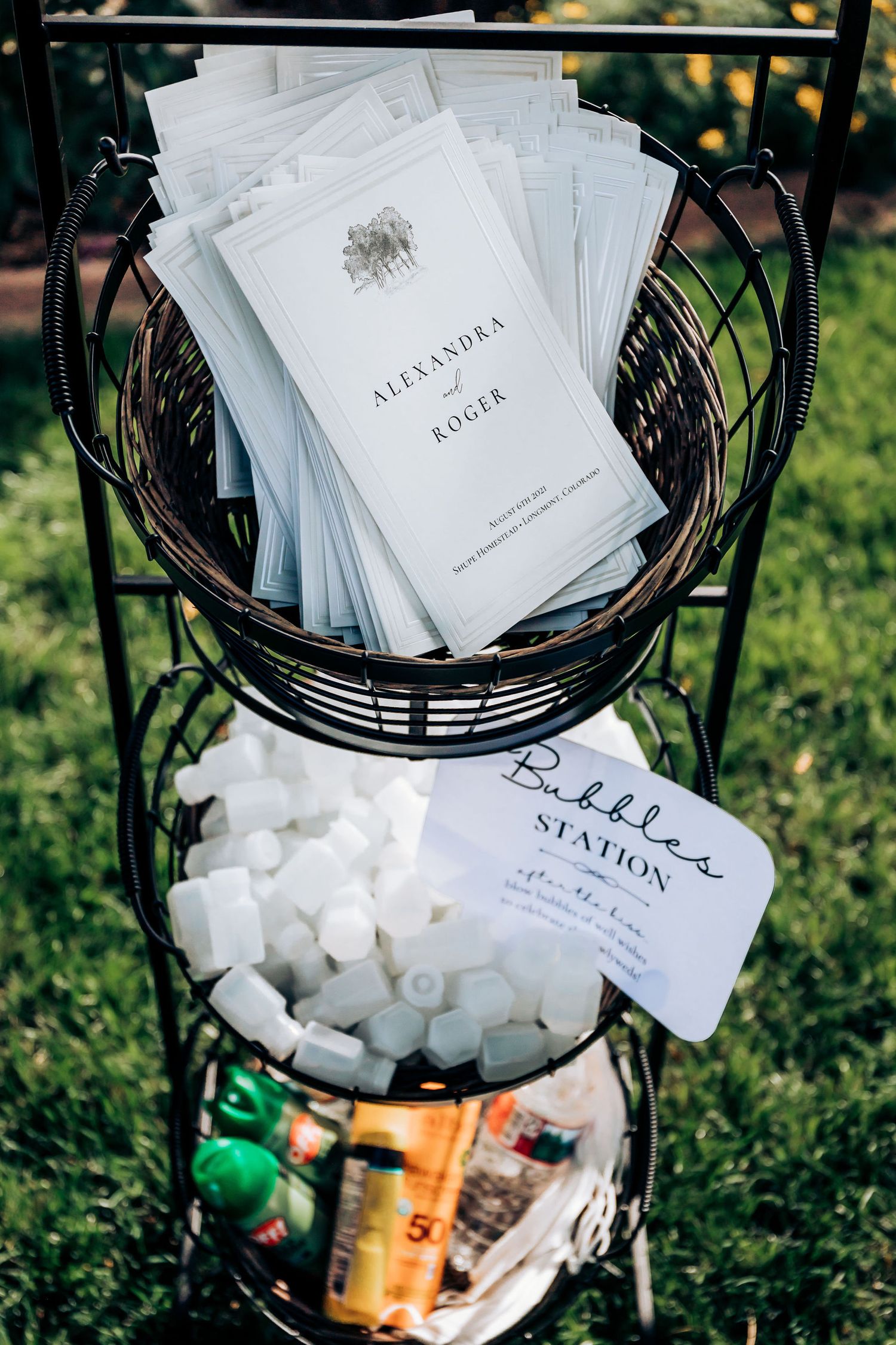 Wedding programs and s'mores supplies arranged in a decorative three-tier metal basket stand.