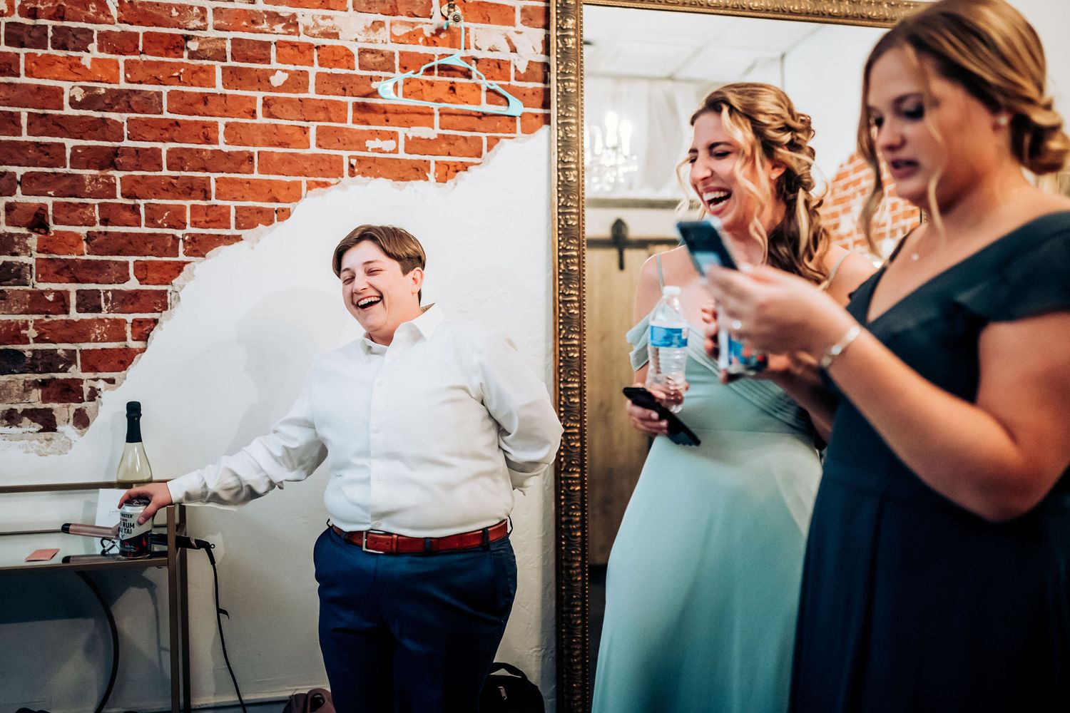 People celebrating in a rustic brick-walled room with vintage mirror.