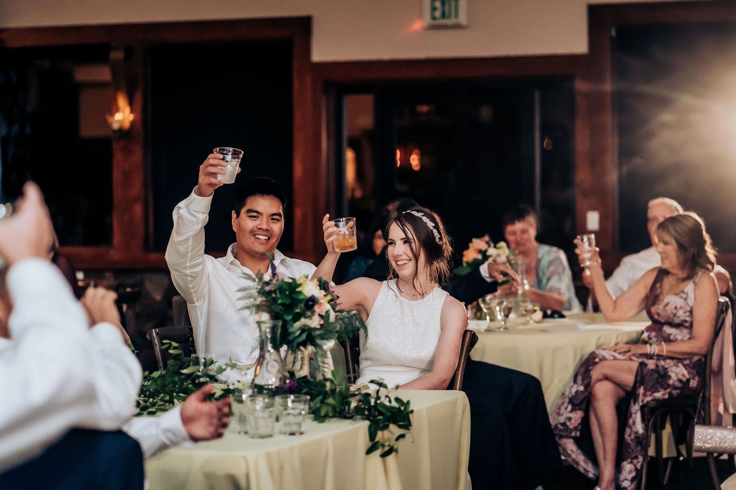 Reception guests raising glasses in a celebratory toast during the wedding festivities.