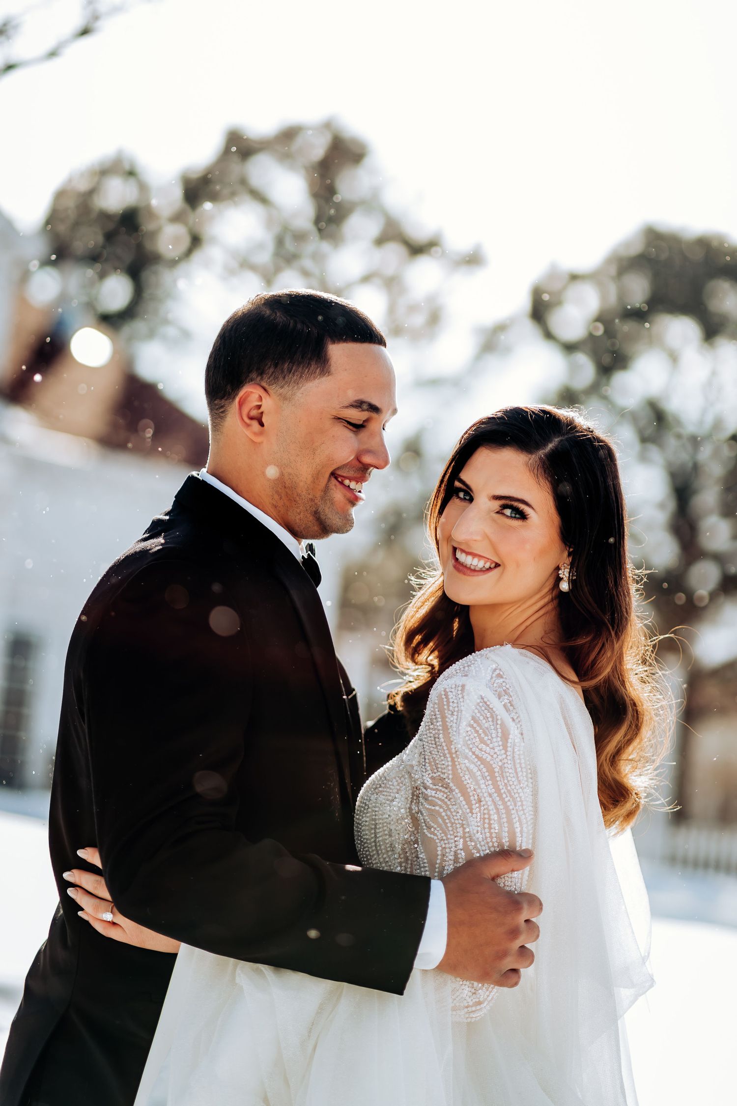 A candid moment between newlyweds sharing laughter in a snowy outdoor setting.