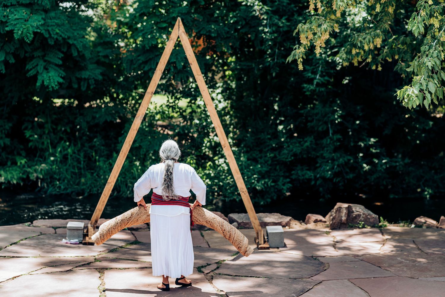 Large wooden triangular arch structure in an outdoor garden setting.
