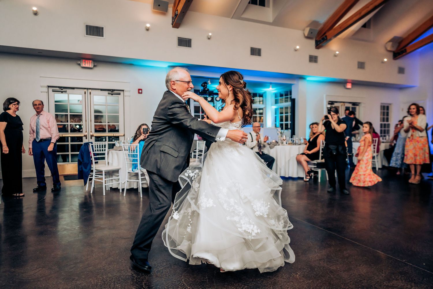 Couple dancing on dark wooden floor during wedding reception in elegant venue.