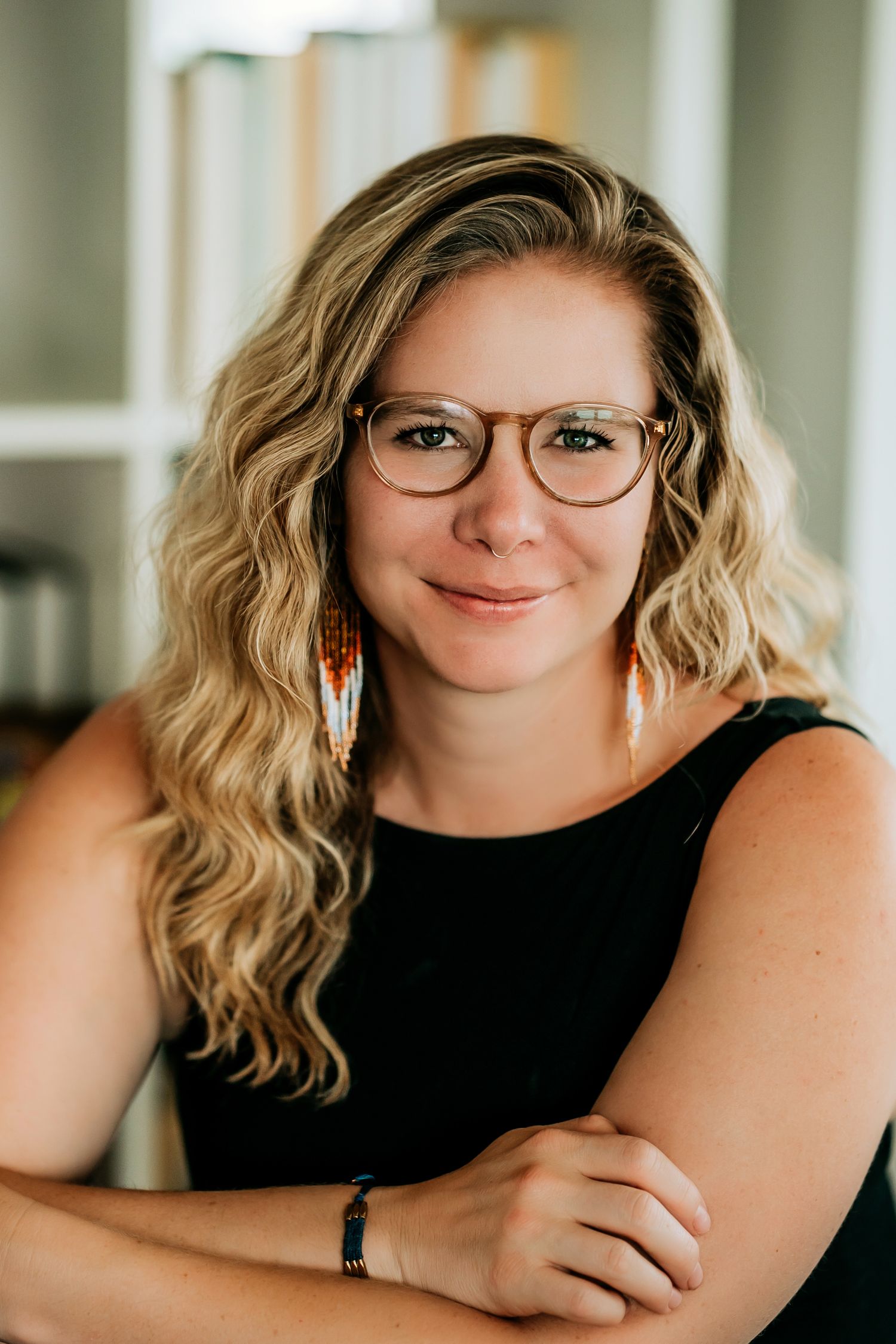 Professional headshot of a creative professional wearing glasses and a black top against a light background.