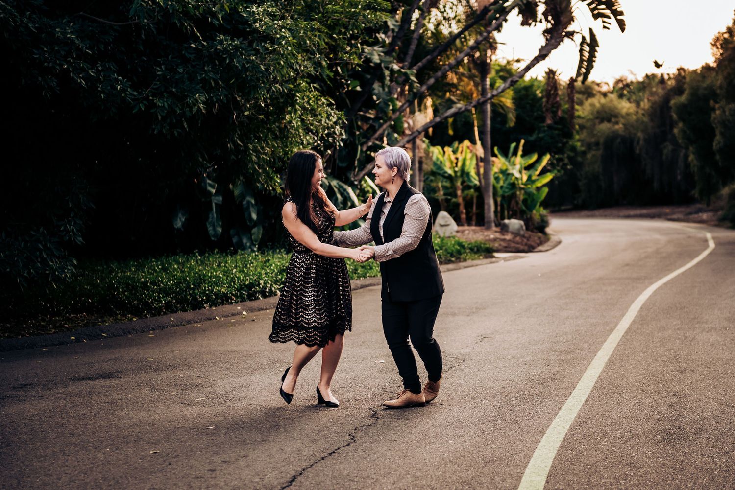 A couple dancing together on a curved garden path surrounded by lush vegetation.