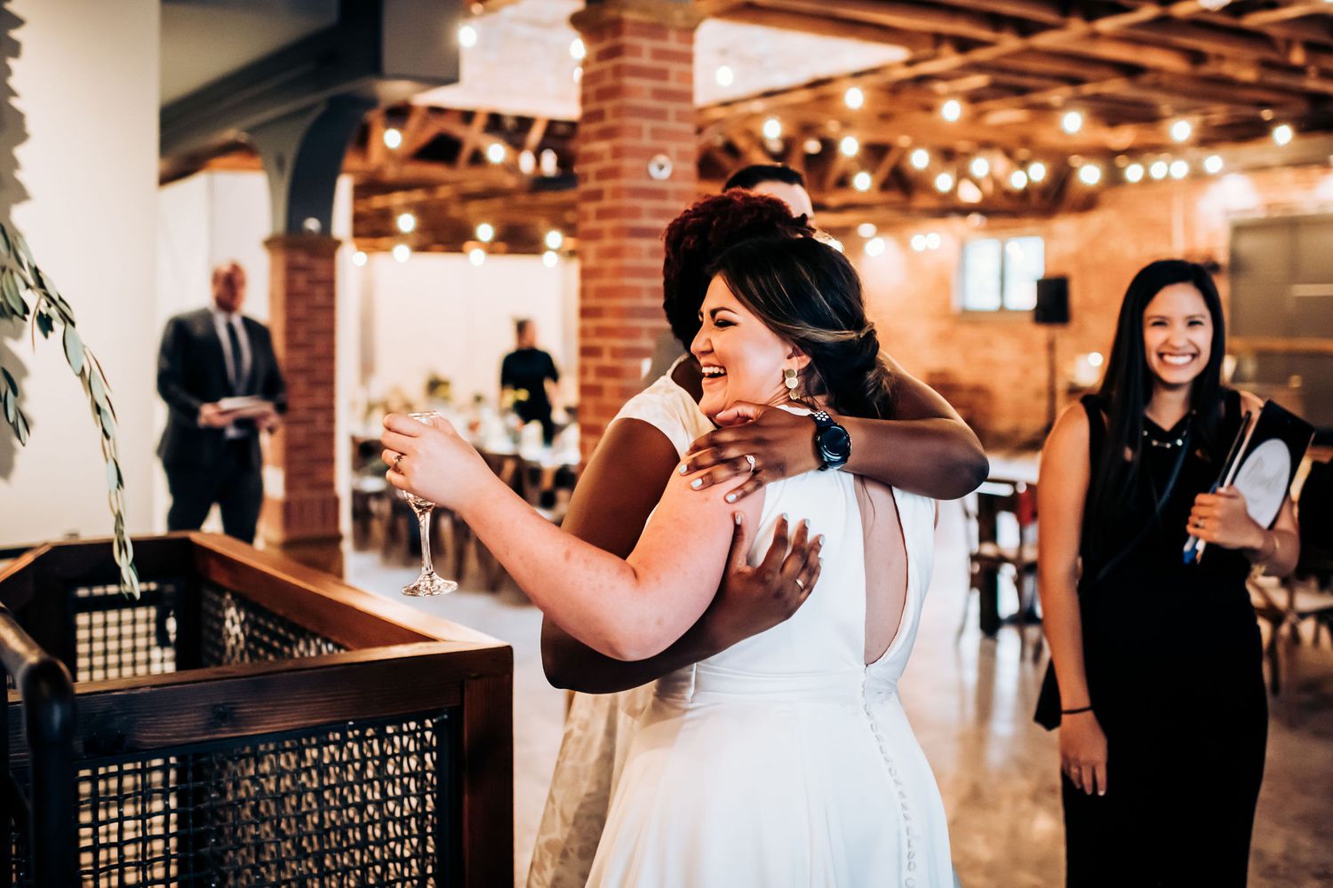 Emotional moment during wedding reception in industrial venue with brick walls and warm lighting.