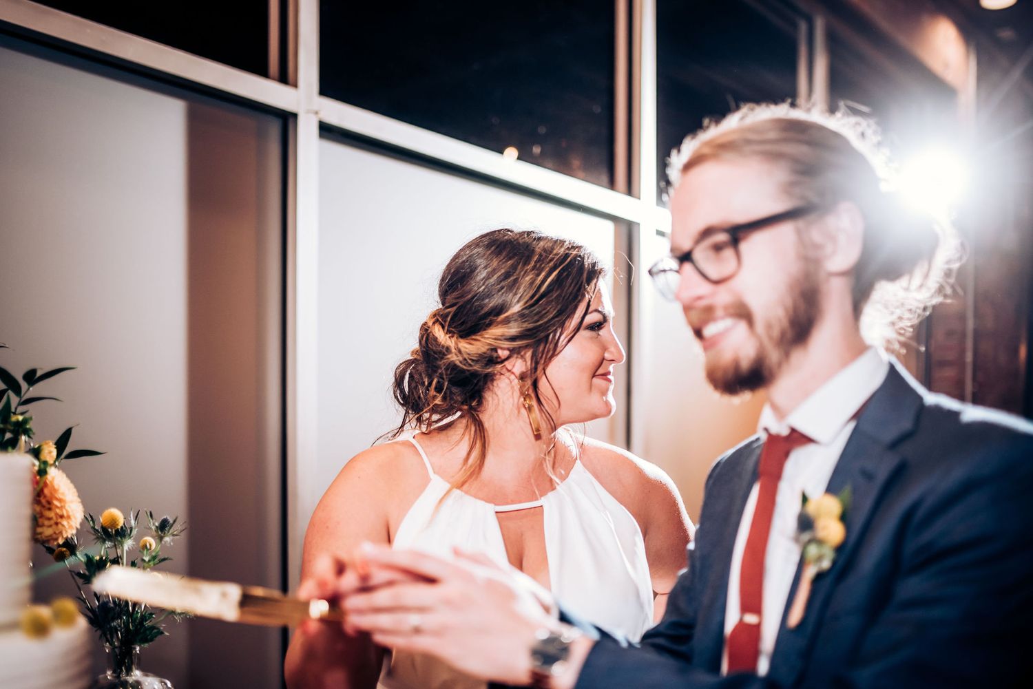 Happy couple shares intimate moment while cutting their wedding cake.
