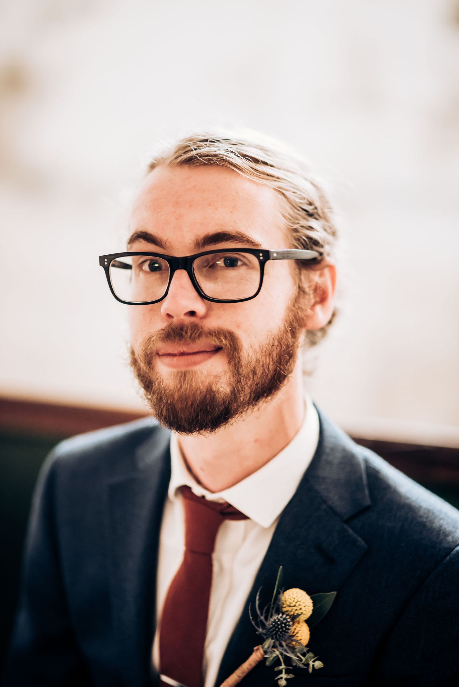 Modern groom in navy suit and burgundy tie poses in contemporary wedding portrait.
