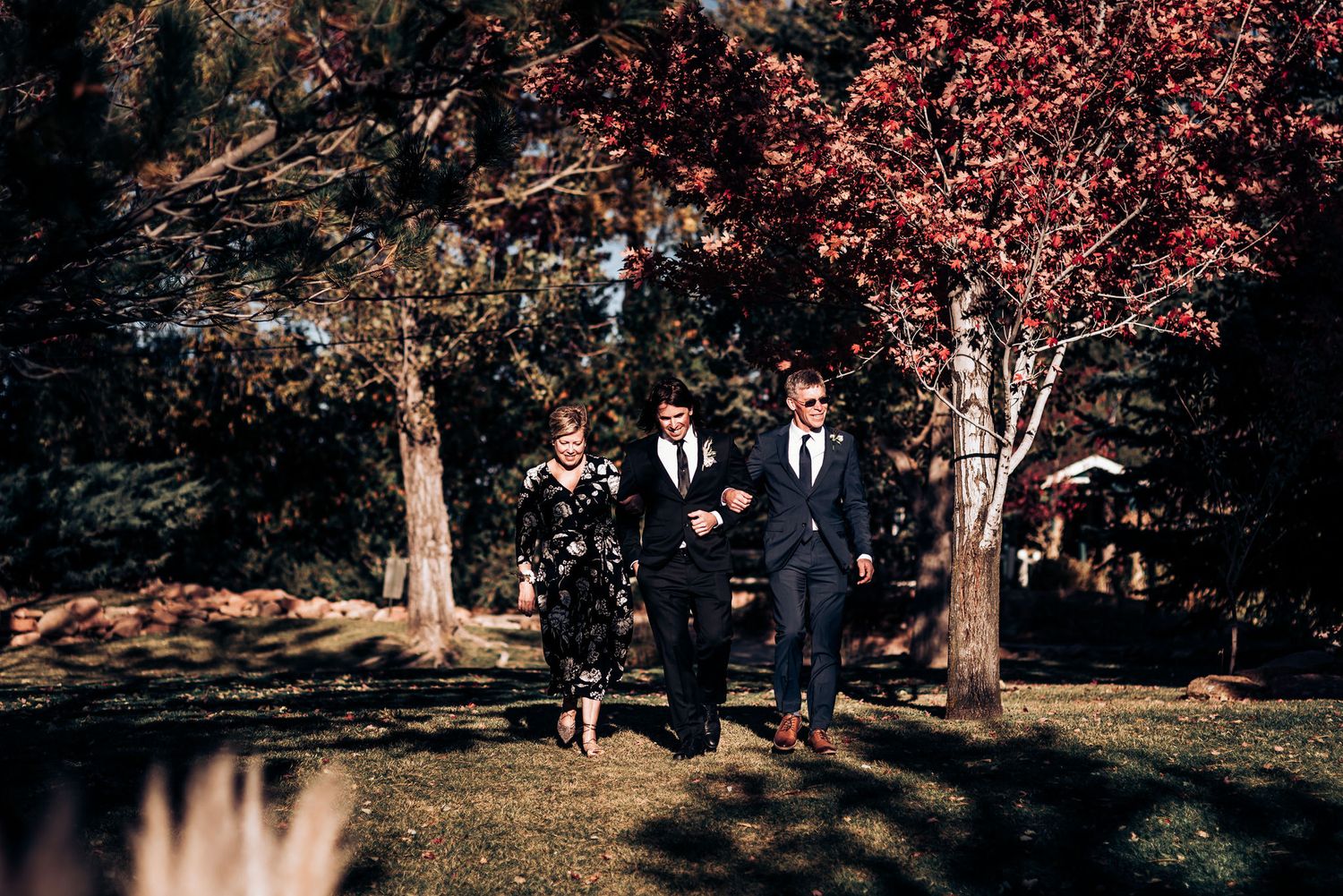Two people walking together through a tree-lined path during an autumn wedding.