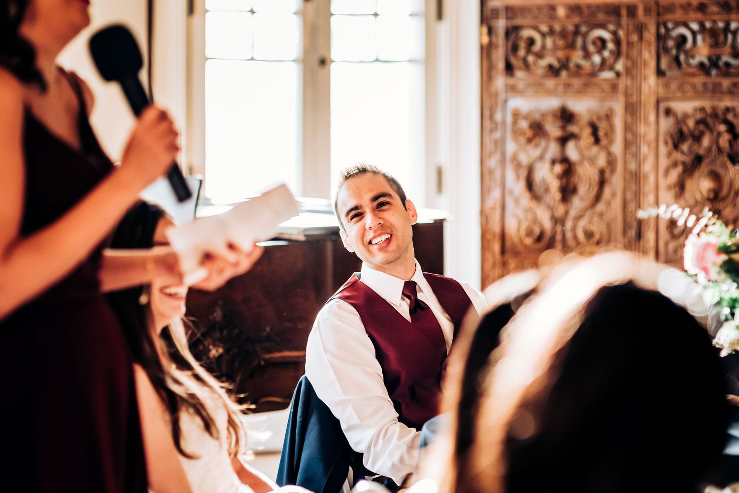 Speech being delivered during wedding reception dinner in elegant venue with carved wooden details.