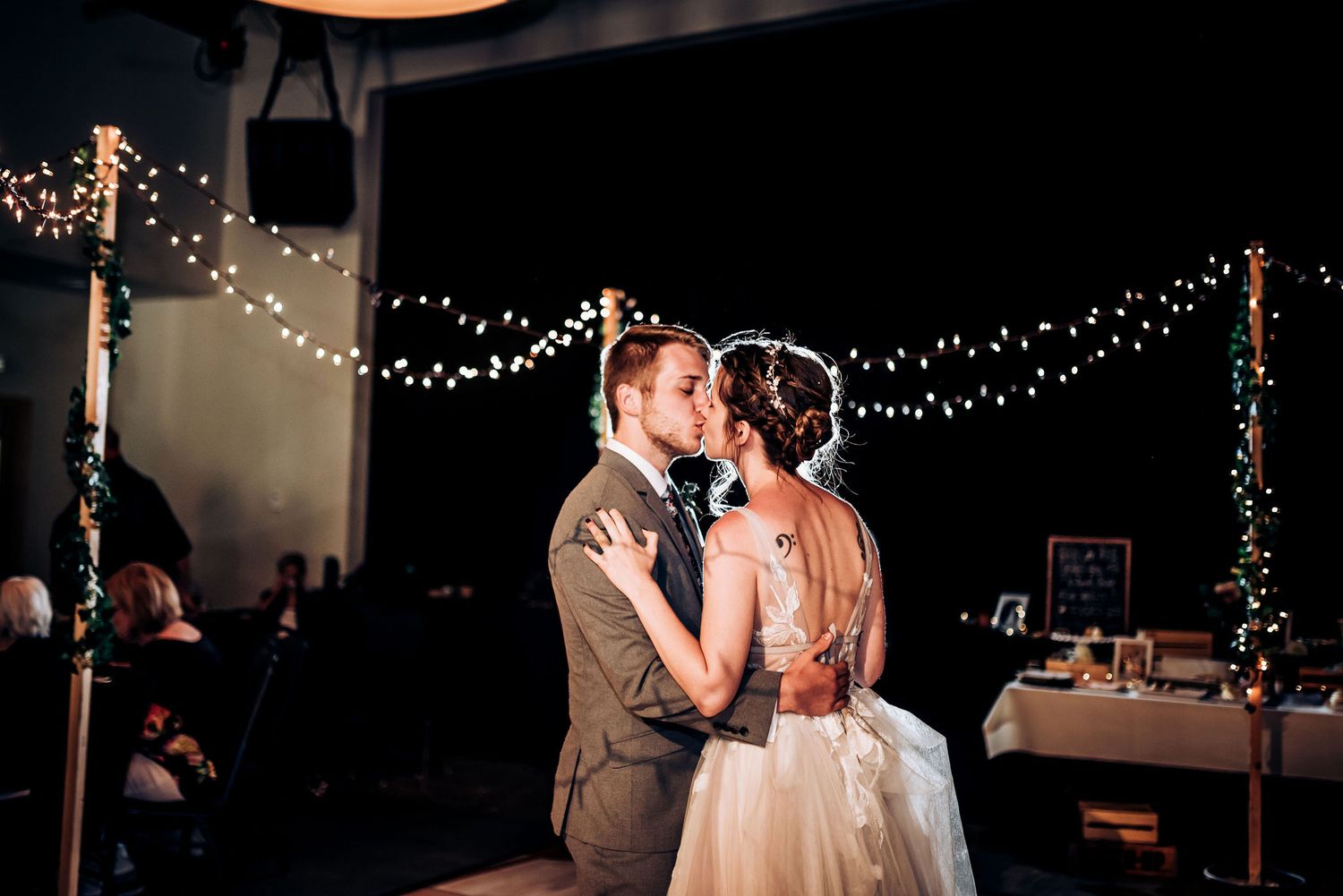 Romantic dance moment captured under warm string lights at wedding reception.