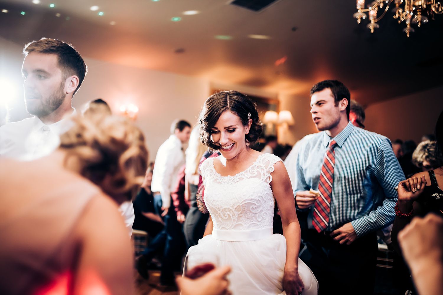 Wedding celebration on the dance floor with guests dancing under elegant lighting.
