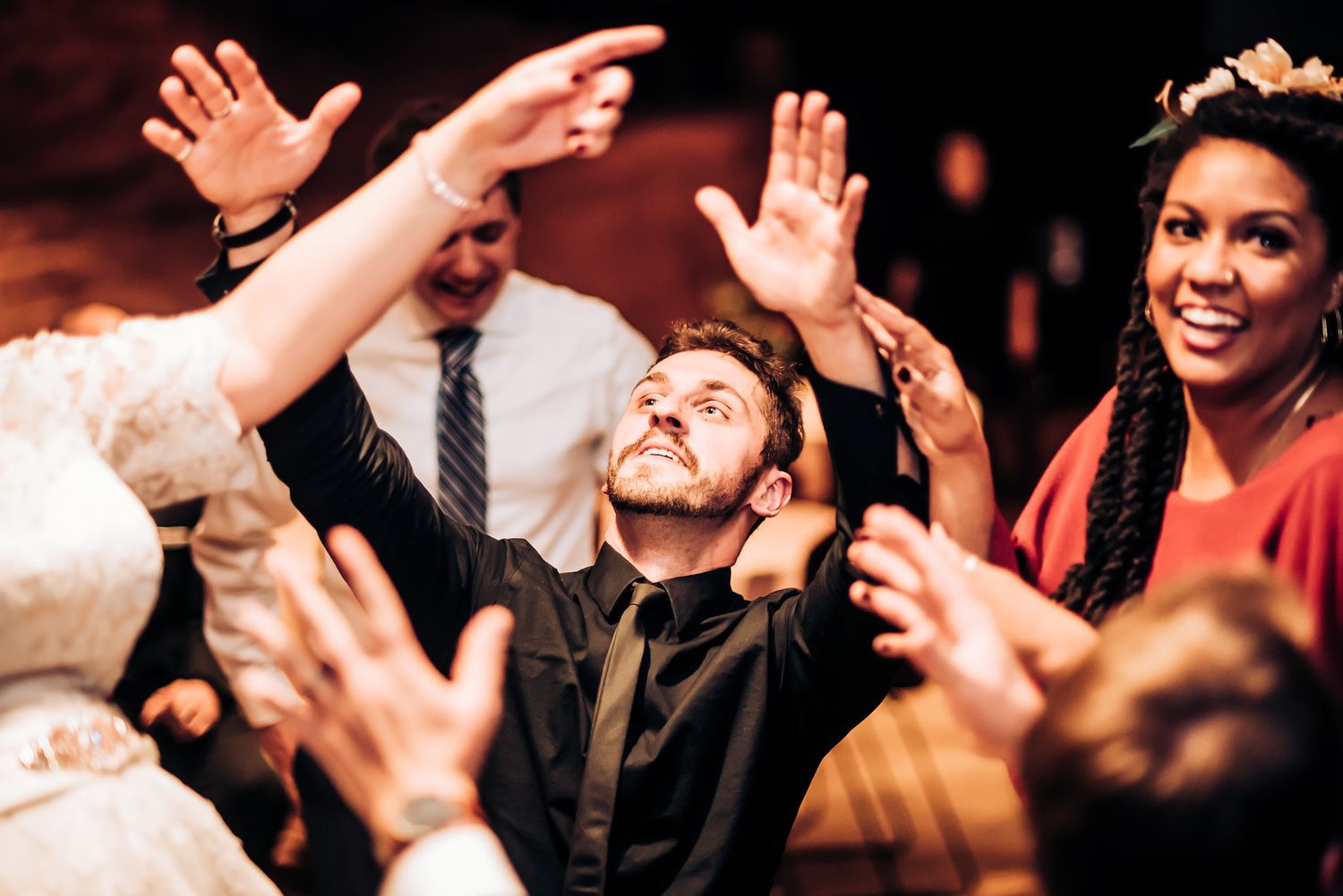 Celebration attendees raise their hands in joy during indoor party event.