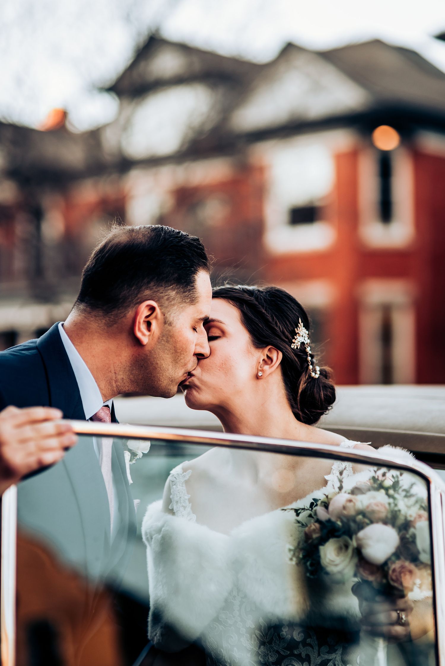 Romantic moment captured through classic car window with brick building backdrop.