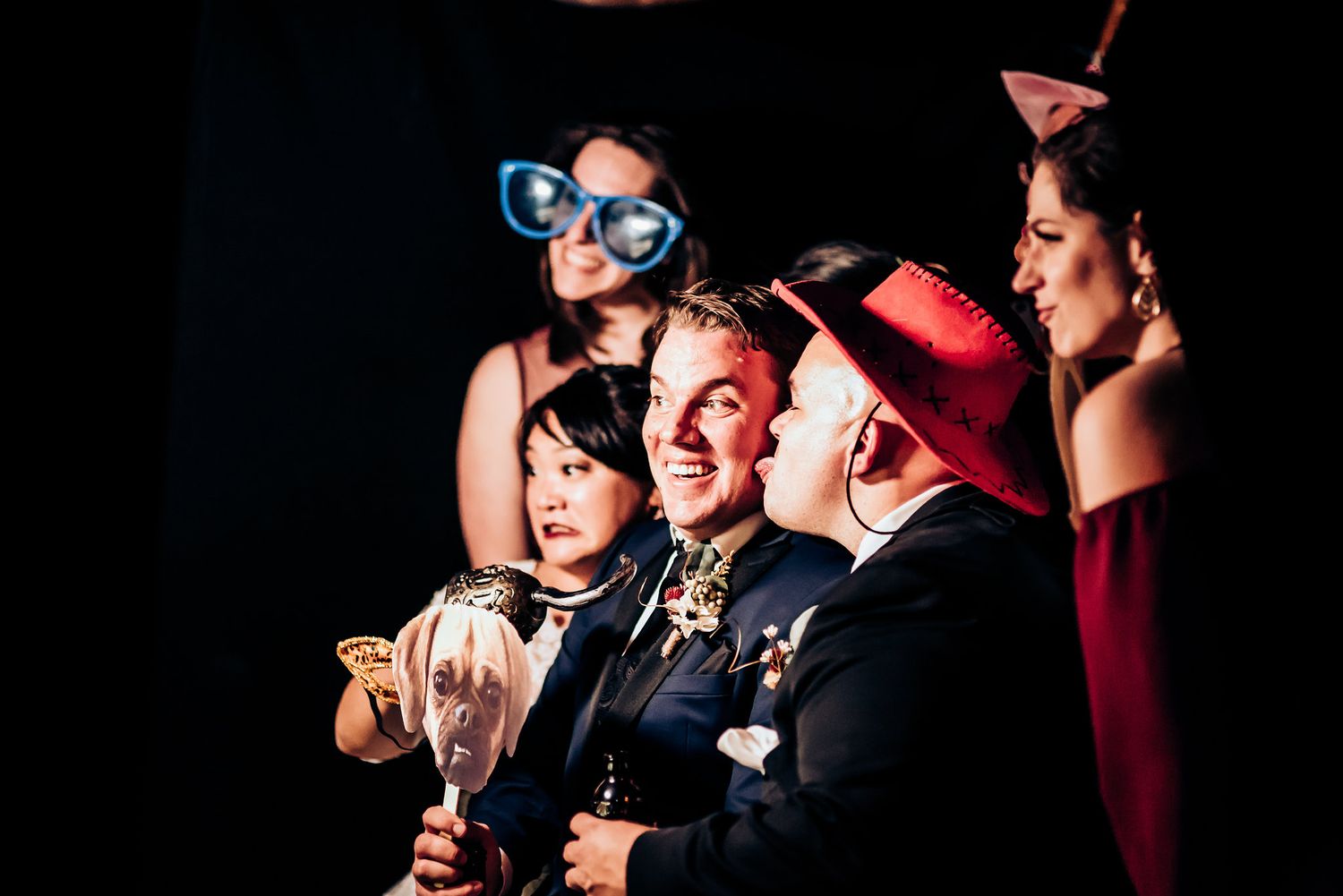 Party guests in formal wear and fun accessories celebrating with champagne.