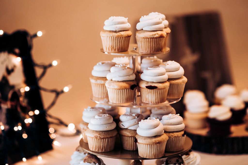 Elegant display of vanilla frosted cupcakes arranged on a tiered wedding dessert stand.