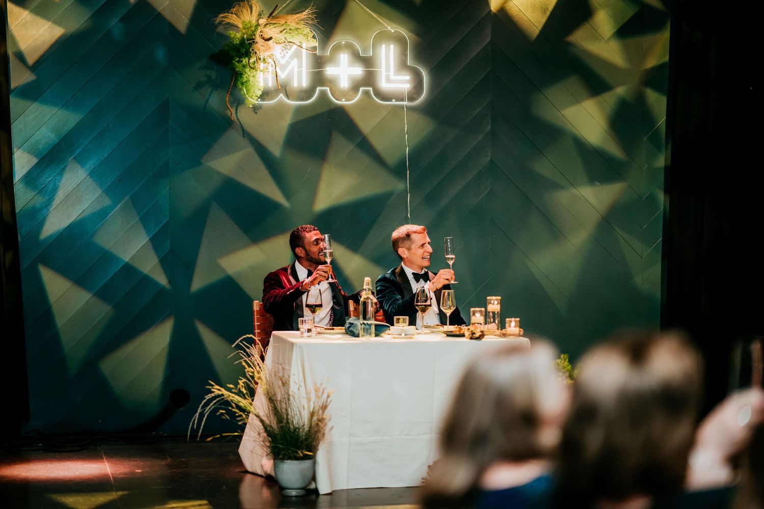 Event setup featuring a white tablecloth and geometric backdrop with M+L signage.