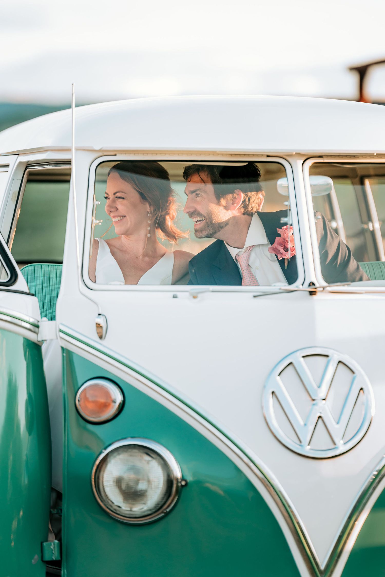 A couple sharing joyful laughter inside a vintage mint green and white Volkswagen van.