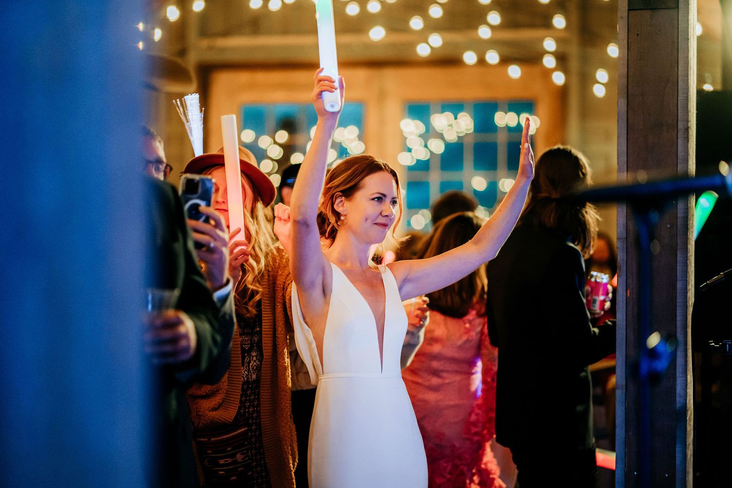 Celebration with glowing light sticks and string lights at evening party venue.