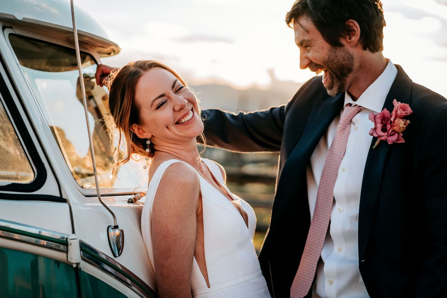 A joyful moment shared between a couple next to a vintage Volkswagen van during sunset.