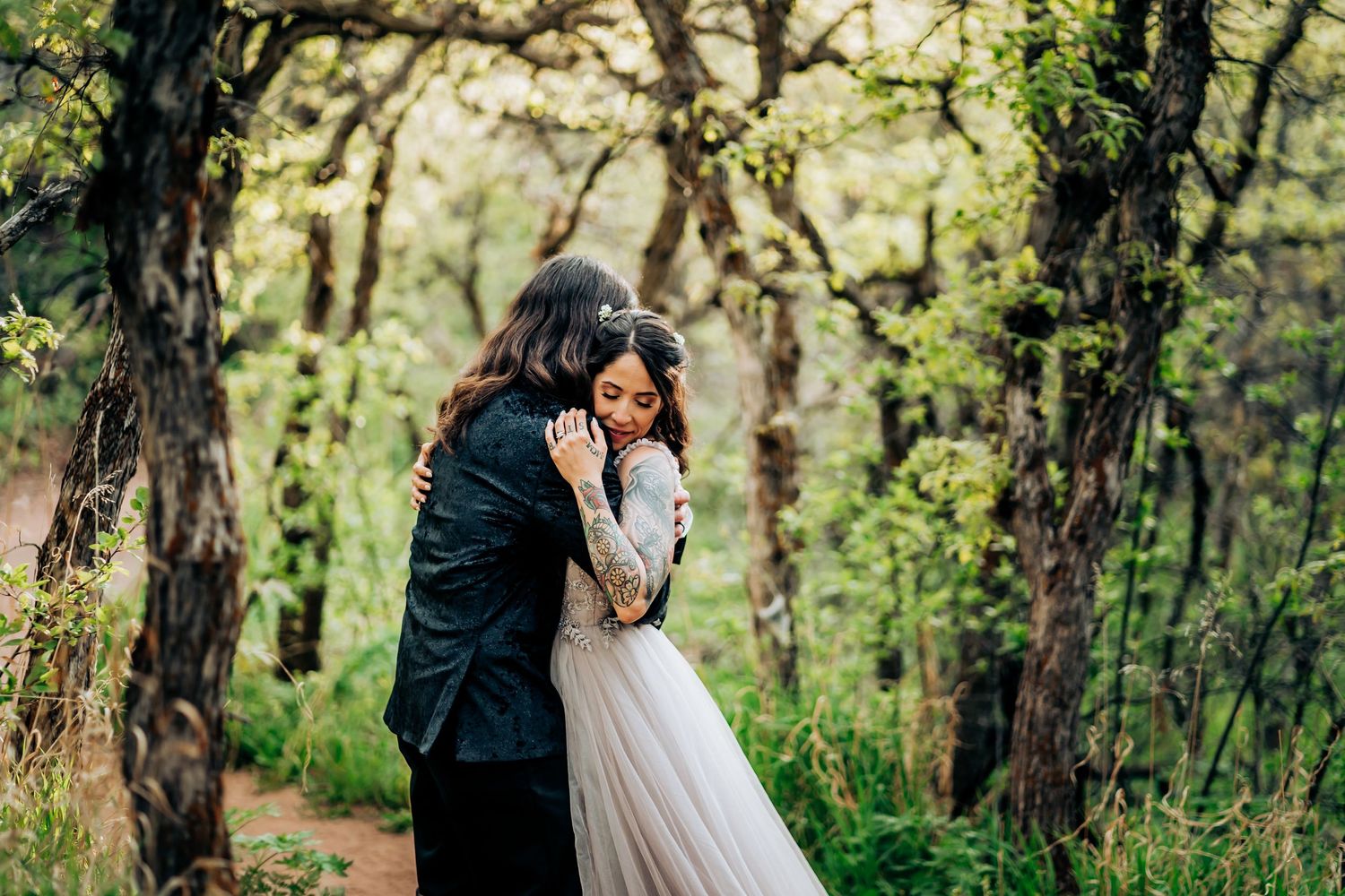 Romantic wedding couple embraces under trees in a dreamy forest setting.