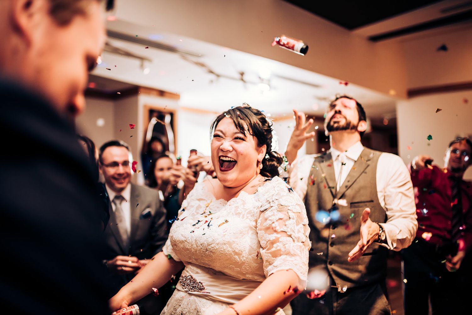 Candid moment of pure joy and laughter during a lively wedding reception party.