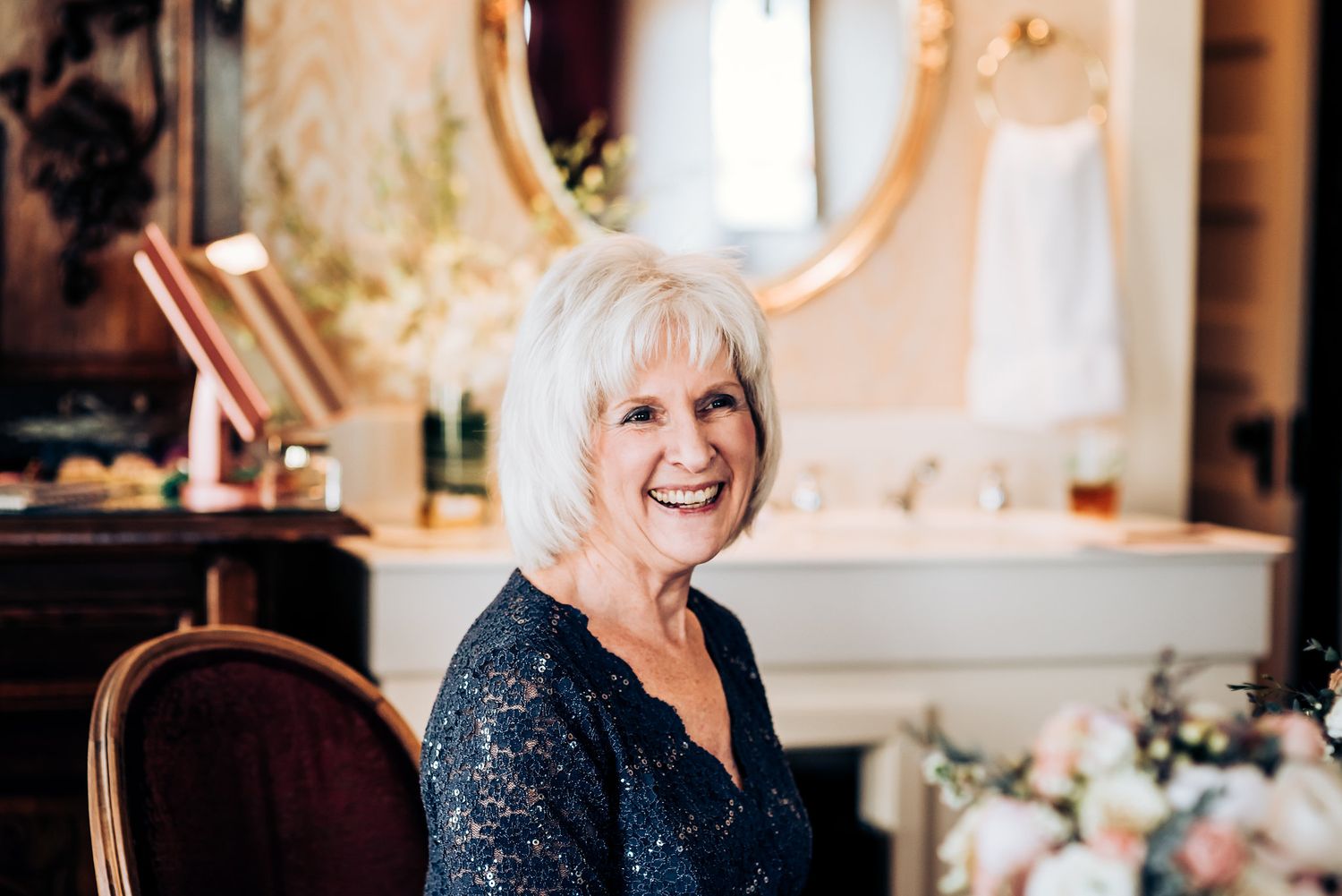 A joyful moment captured near an elegant vanity mirror during wedding preparations.