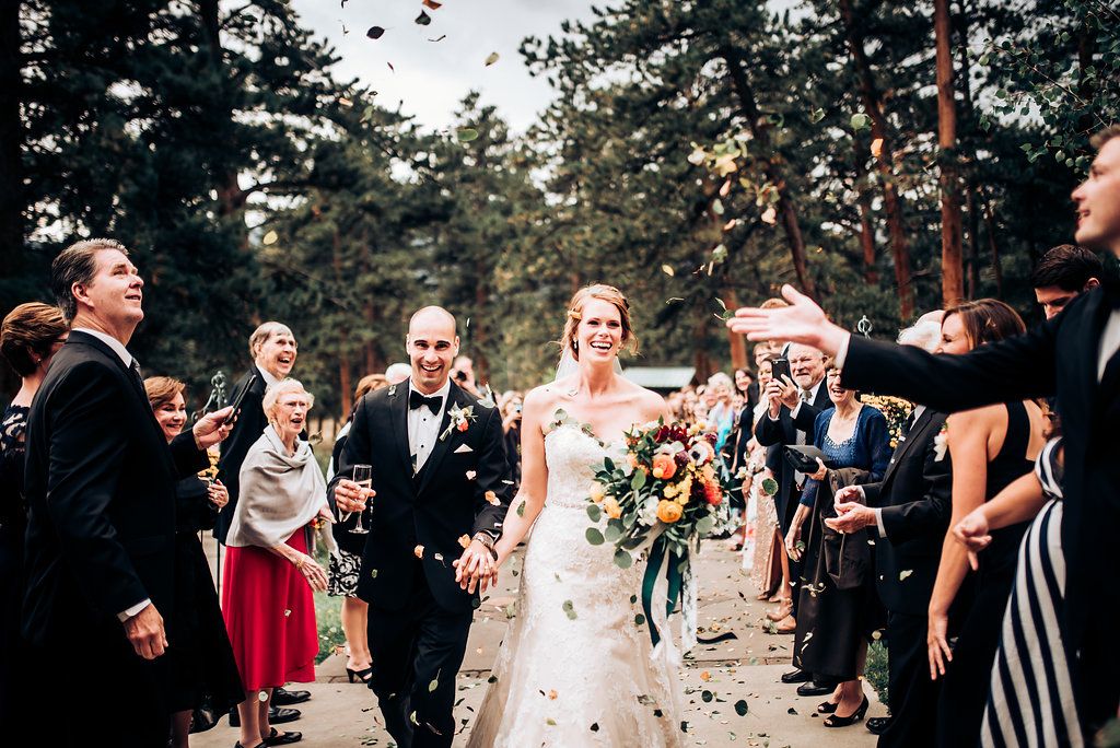 Guests shower rose petals on the wedding couple during their outdoor woodland ceremony exit.