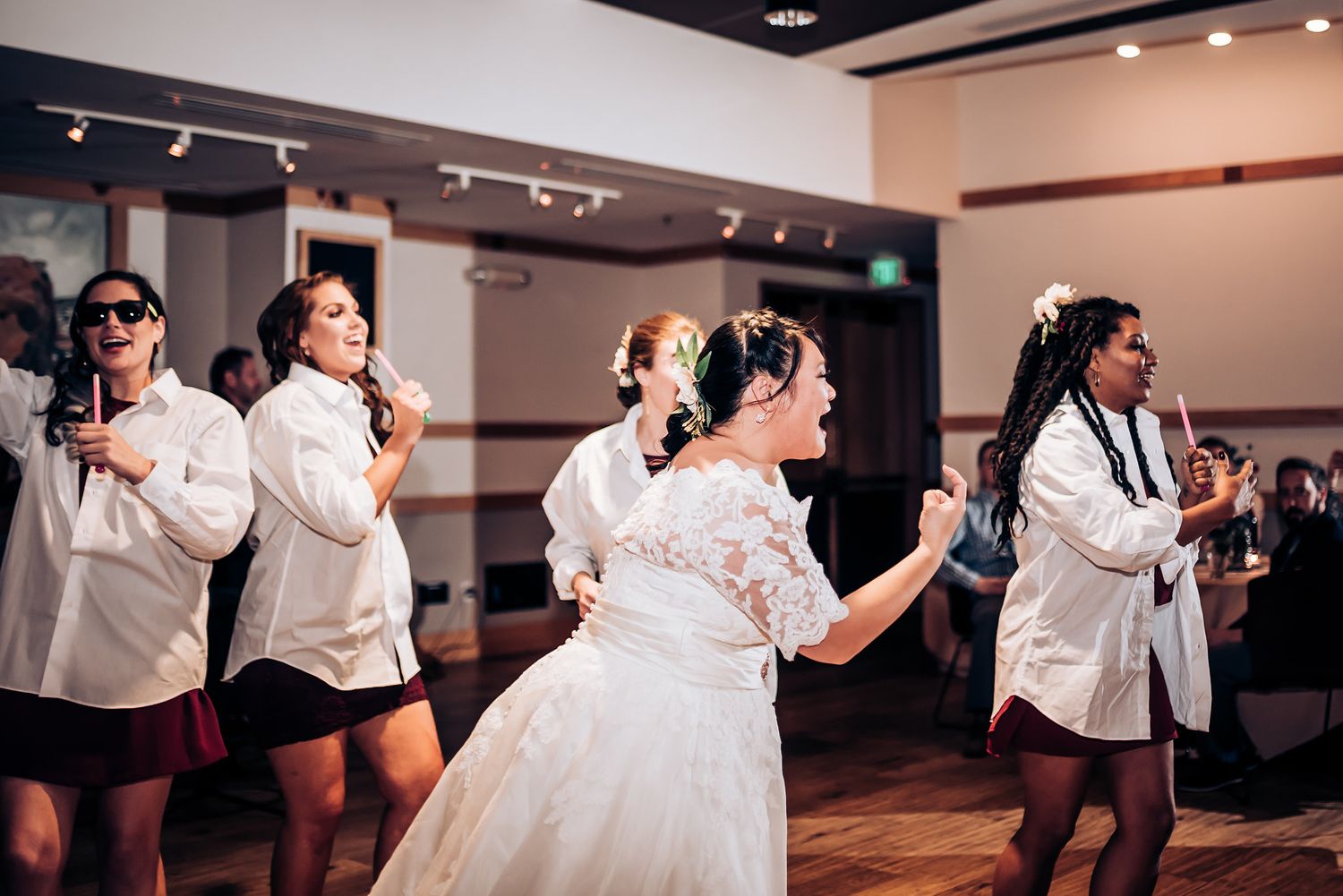 Dancers perform choreographed moves alongside a bride during a wedding reception.
