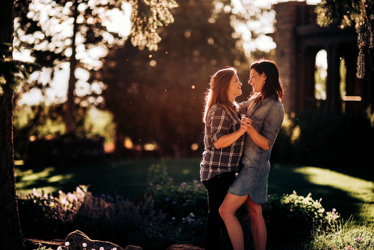 Two people embrace in a romantic garden setting during golden hour.