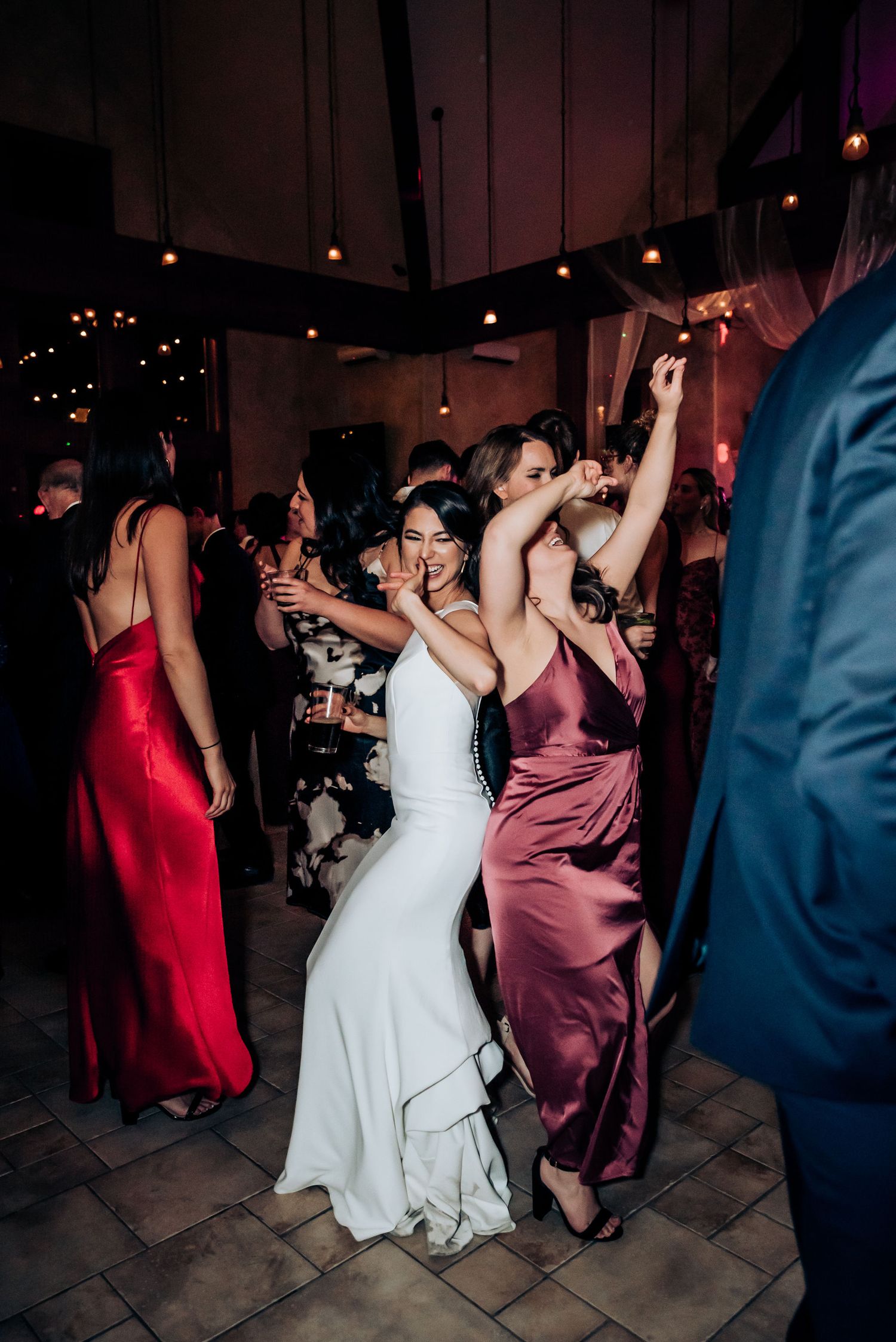Wedding party dancing together in elegant dresses and formal attire.