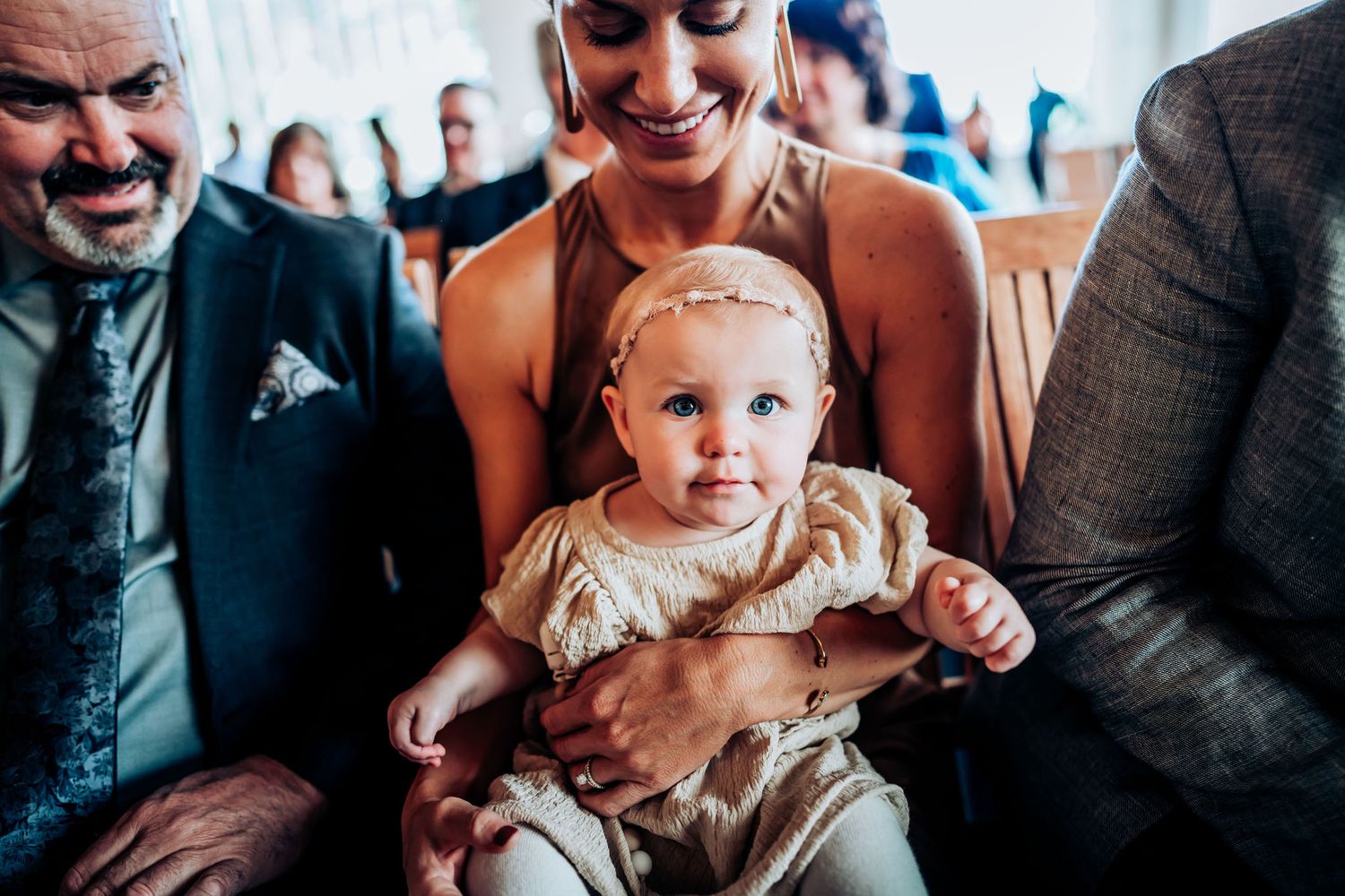 Joyful moment during wedding reception with baby in cream-colored outfit.