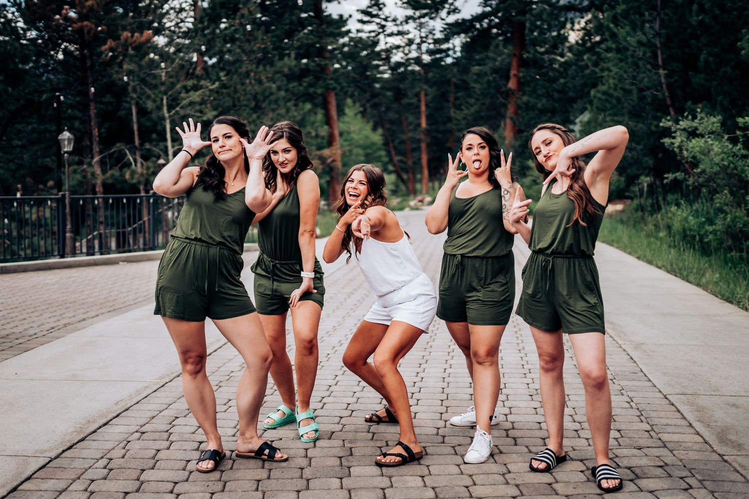 A fun group photo showing people in matching olive green outfits posing playfully on a brick pathway.