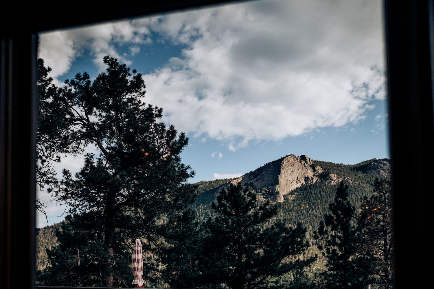 Mountain landscape view through a window frame showing rocky peaks and blue sky.