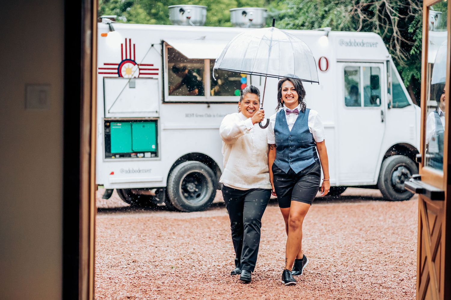 Two figures walking together in front of a white food truck.