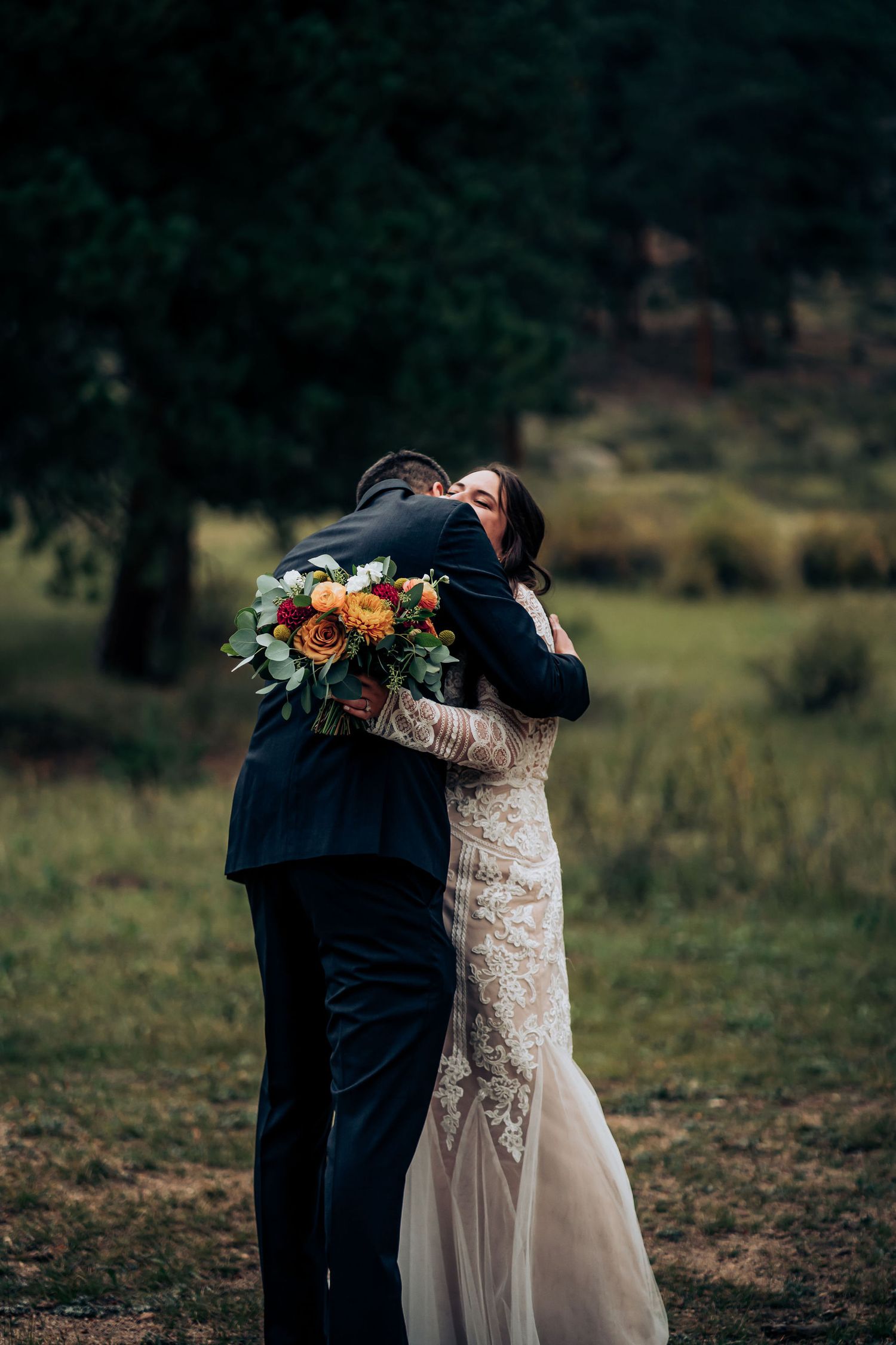 Intimate embrace captured during outdoor forest wedding ceremony with autumn bouquet.