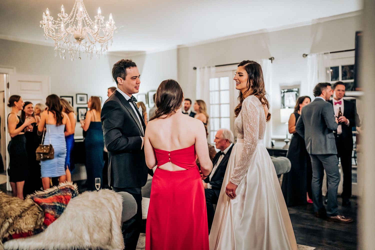 Wedding ceremony in an elegant room with crystal chandelier and guests gathering around the center.