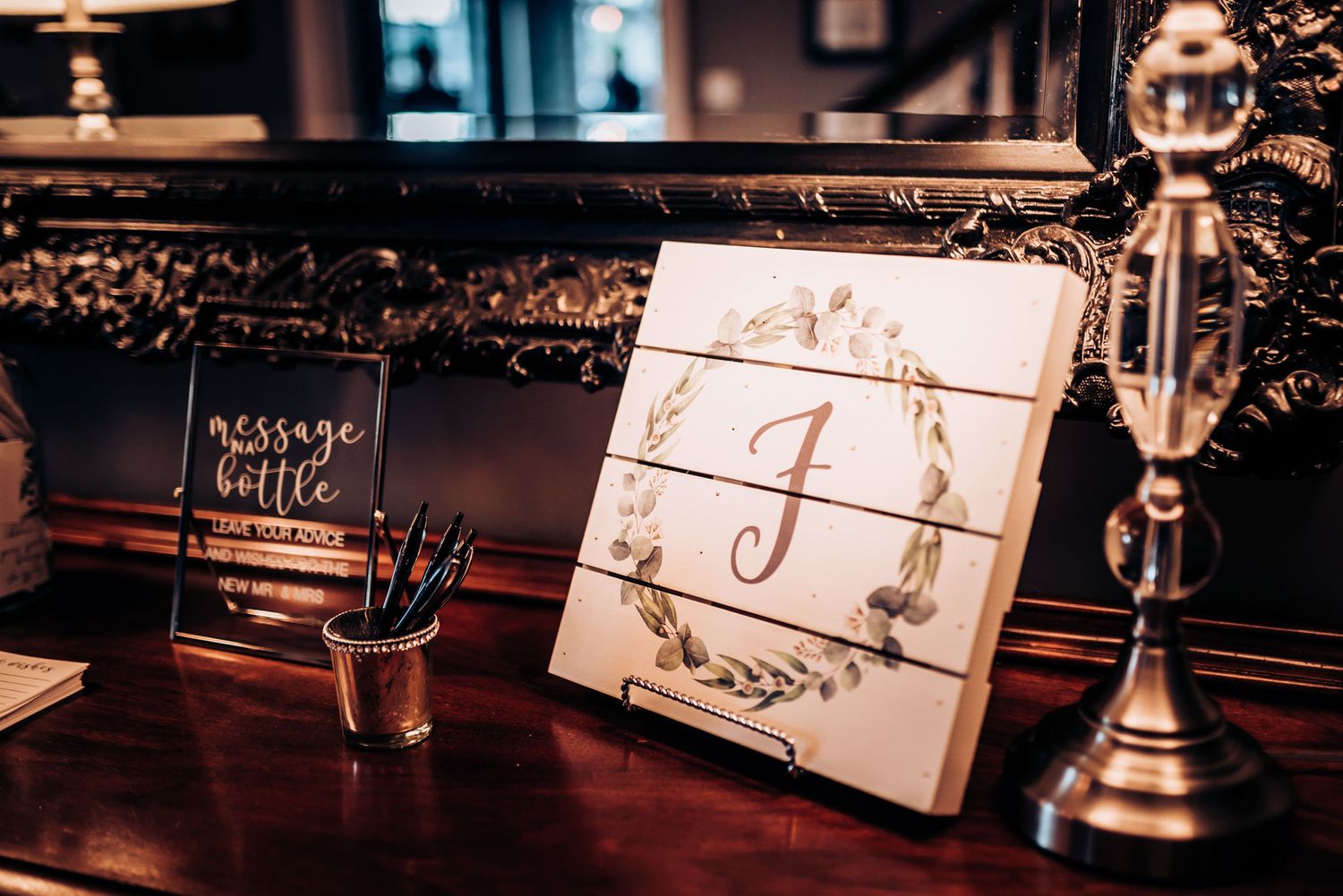 Decorative monogram display with letter J and message bottle sign on wooden table.