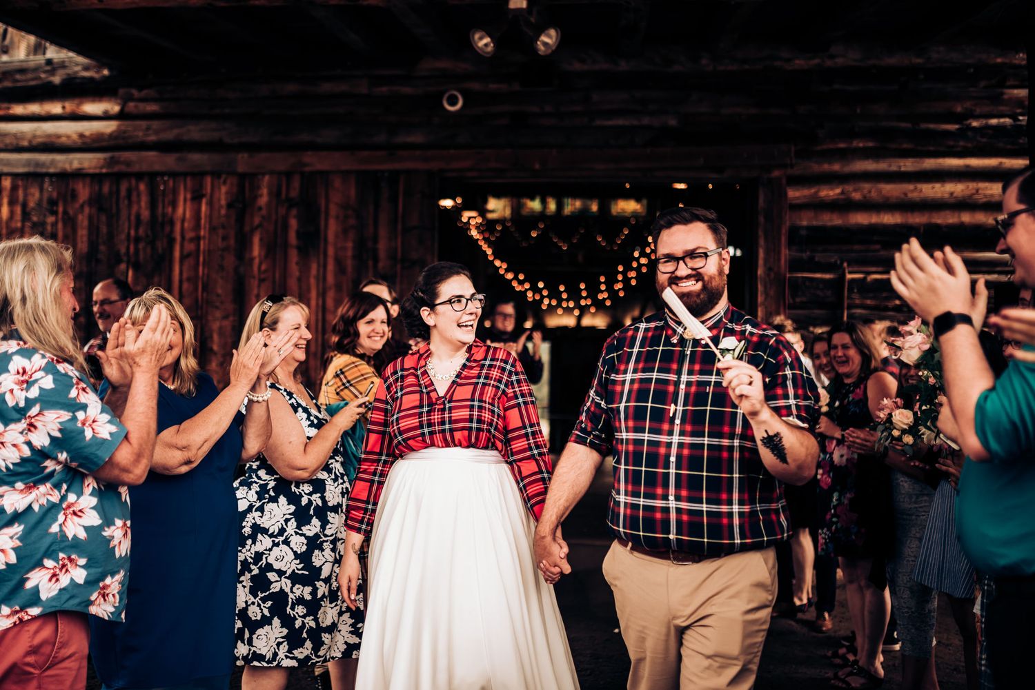 Celebration in rustic venue with guests in floral dresses applauding.
