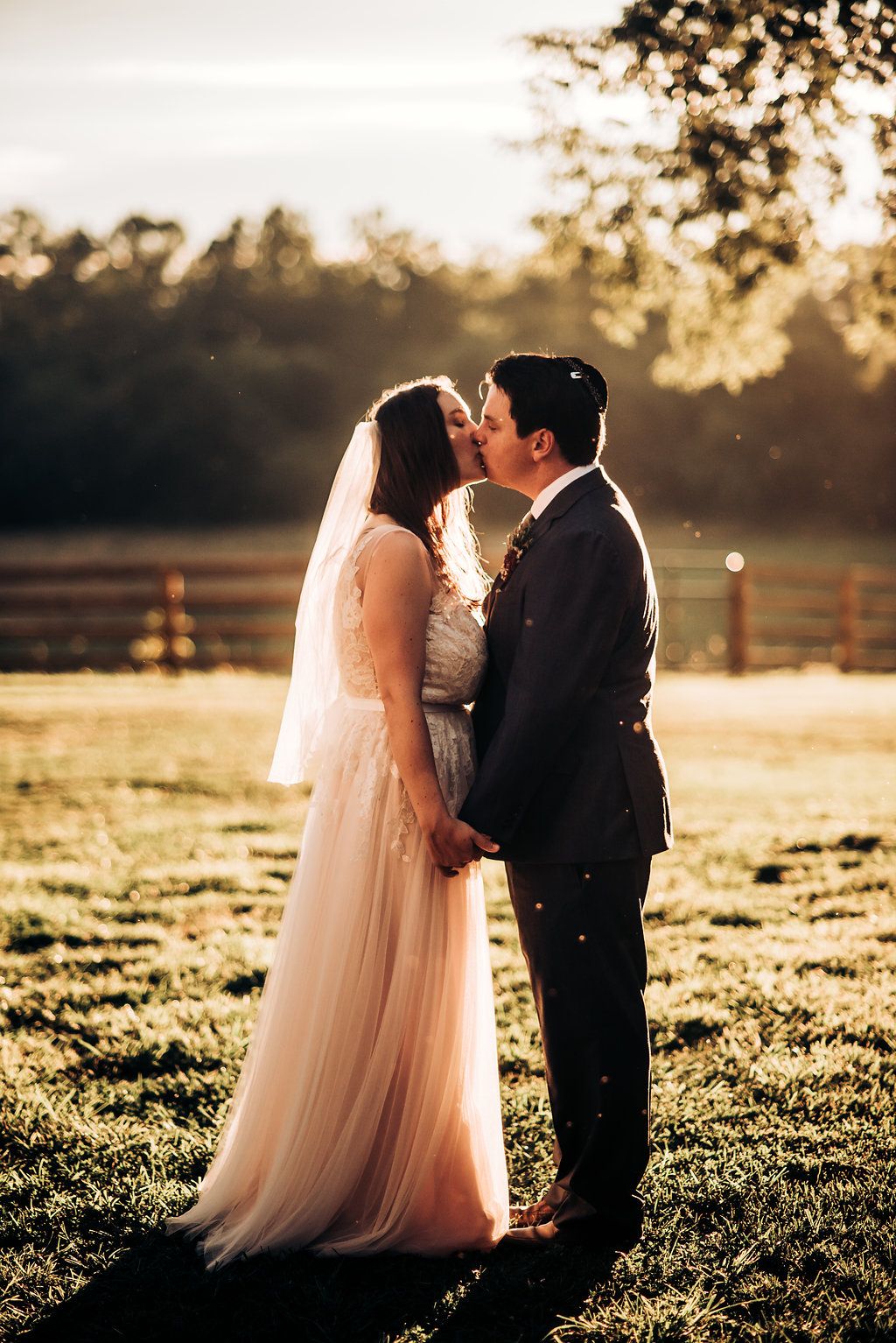 Newlyweds share romantic moment in golden sunlight on their wedding day.