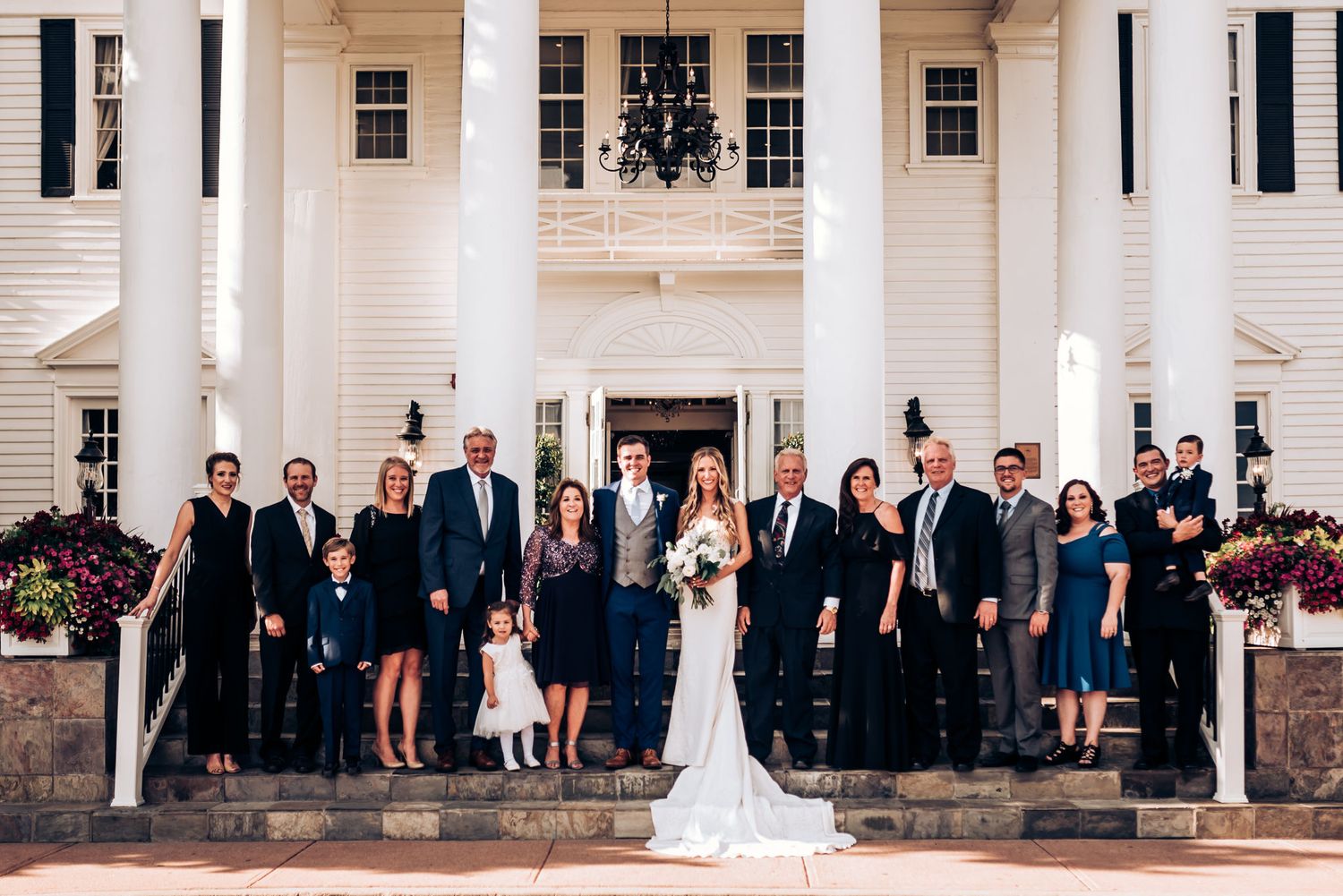 Formal group photo of wedding party on classic white colonial building steps.