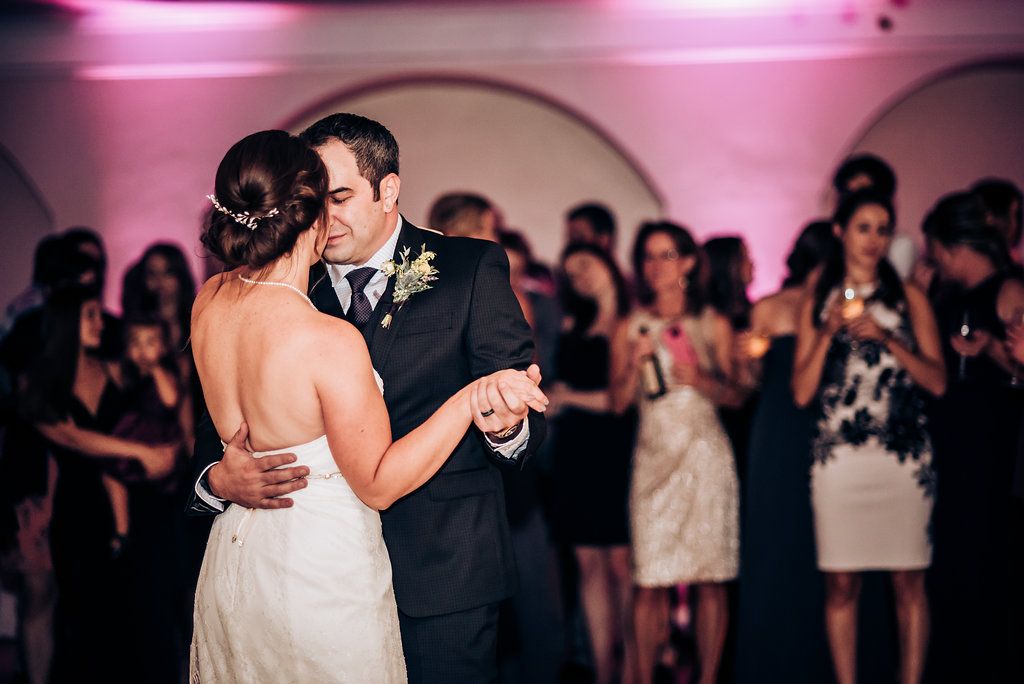 Intimate dance moment captured during wedding reception with guests looking on.