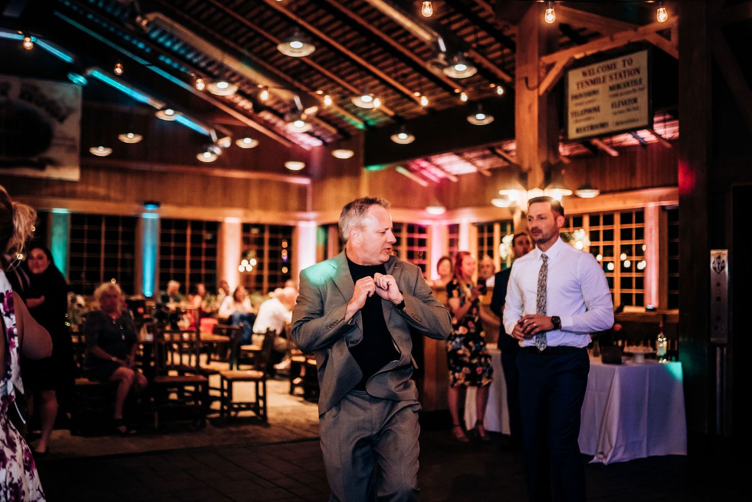 Guest performs karaoke in dimly lit rustic venue with wooden beams.