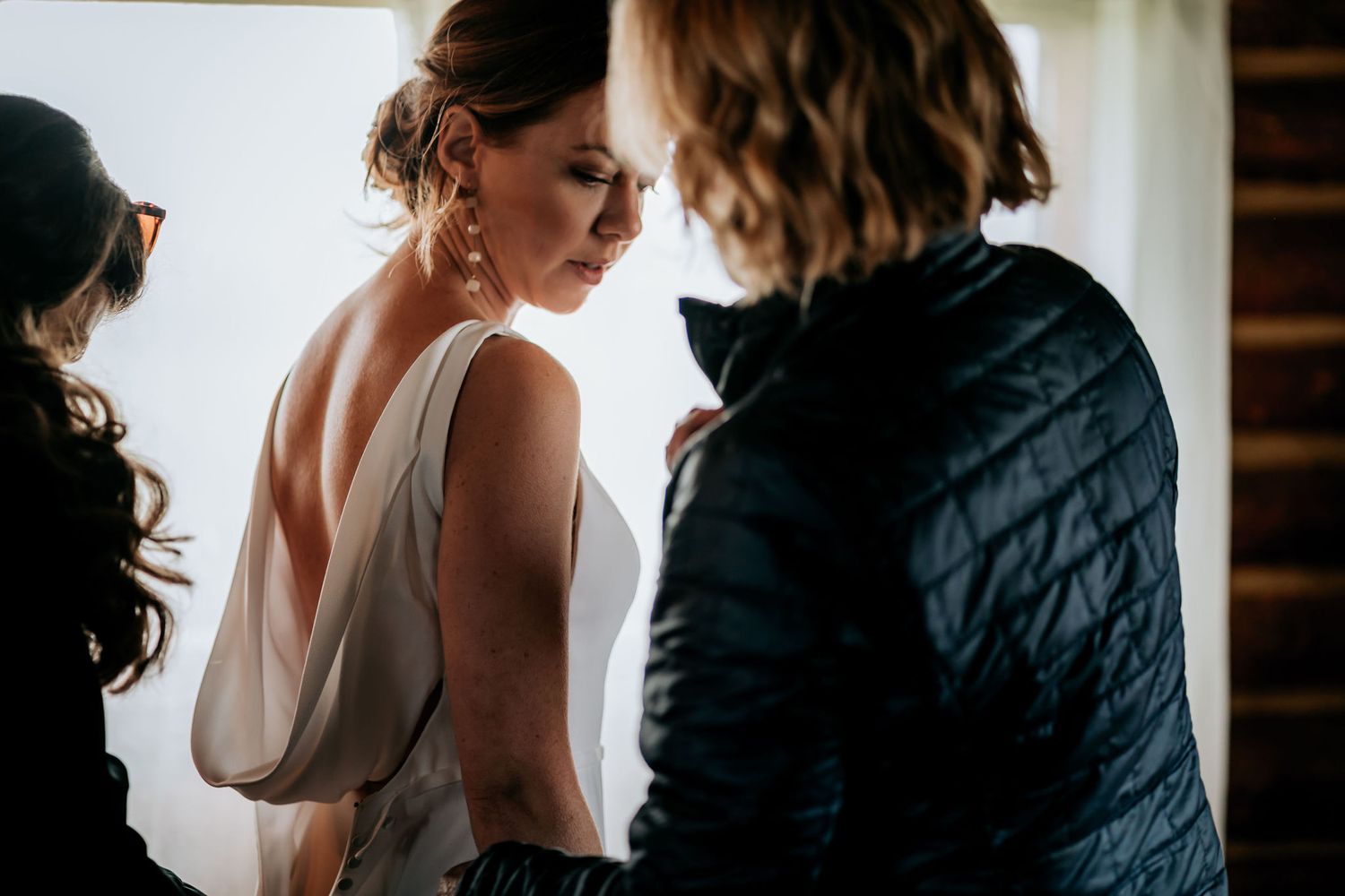 A candid moment showing wedding dress preparations in an intimate indoor setting.